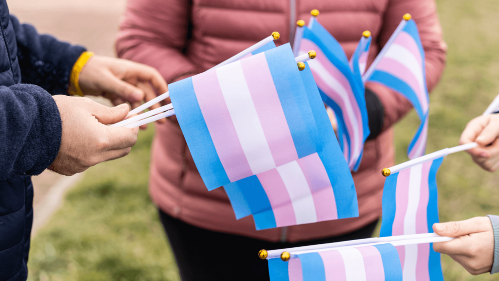 Three people holding small transgender flags