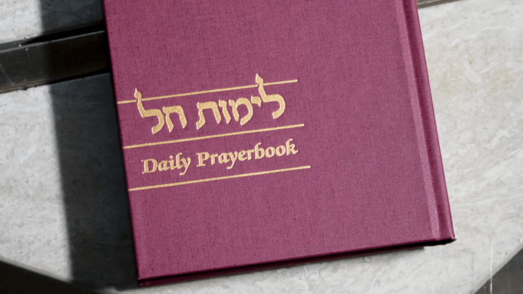 Close-up of a daily prayer book with Hebrew writing in gold on the cover