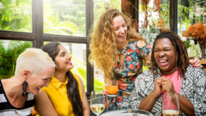 four women sitting around a table laughing and enjoying a meal