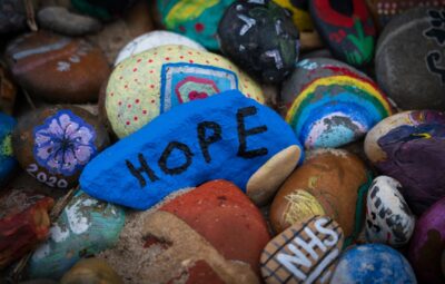 Colorful painted rocks with the word HOPE on a blue stone.