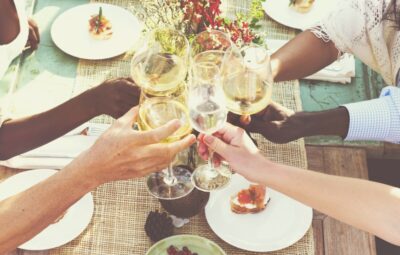 People clinking wine glasses around a decorated outdoor table set for a meal.