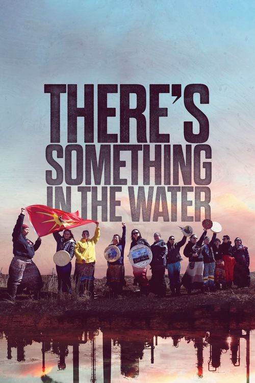 Group of people holding drums and a flag under the title Theres Something in the Water against a sunset sky.