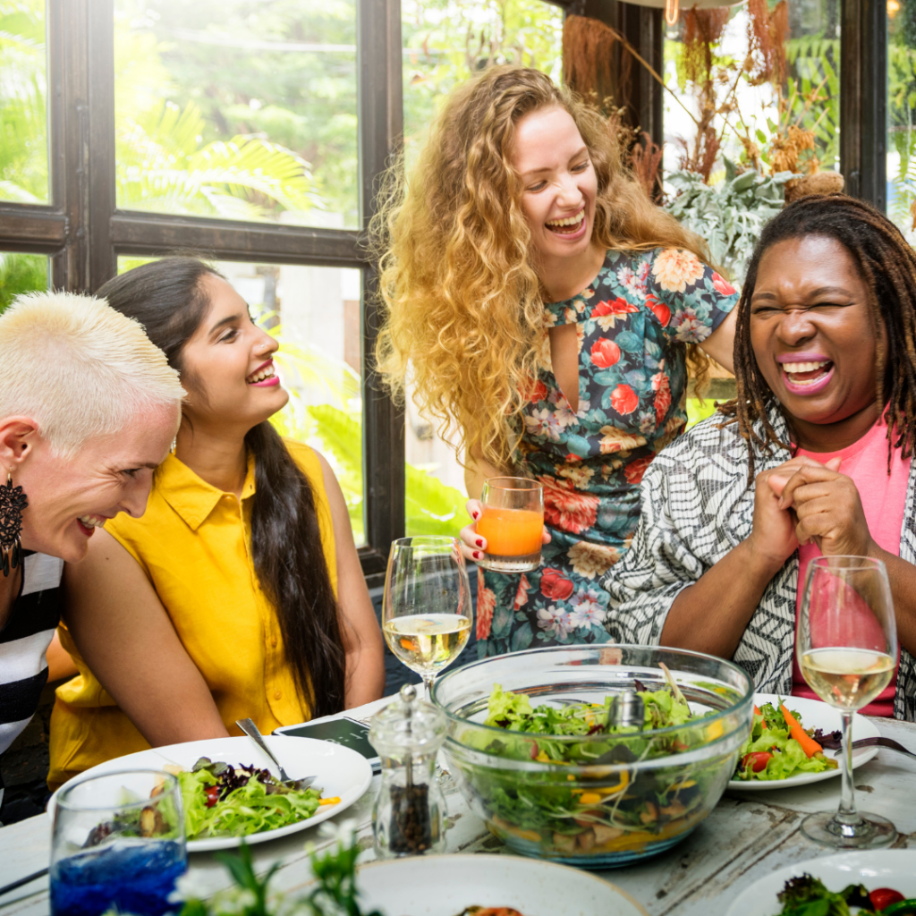 four women sitting around a table laughing and enjoying a meal