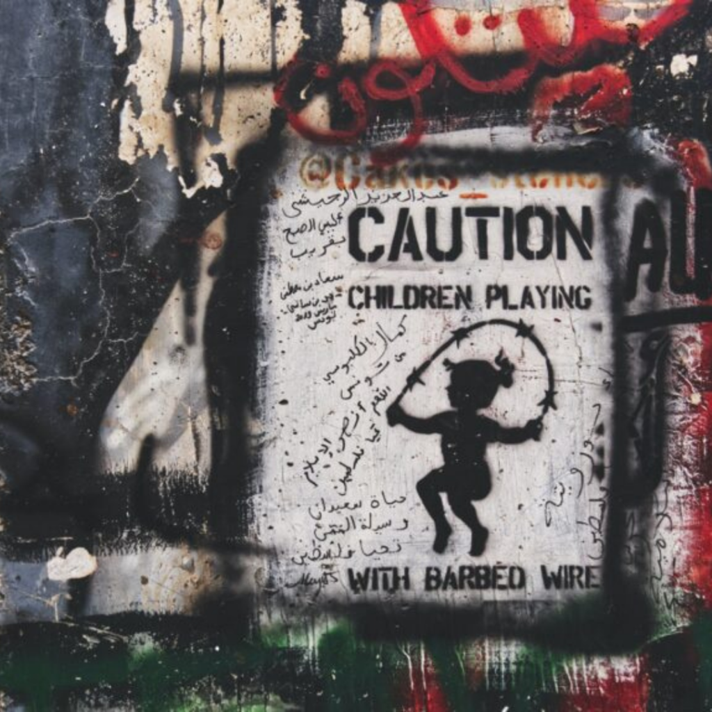 Graffiti of a child playing with barbed wire, surrounded by various writings and grunge textures on a wall.