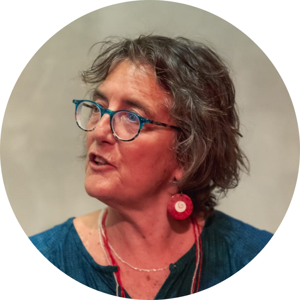 A person with short gray hair, glasses, and red earrings, speaking.