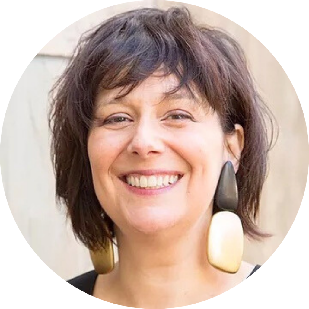Smiling person with short dark hair and large geometric earrings.