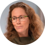 Rabbi Amy Klein with long, wavy hair and glasses looks to the side.