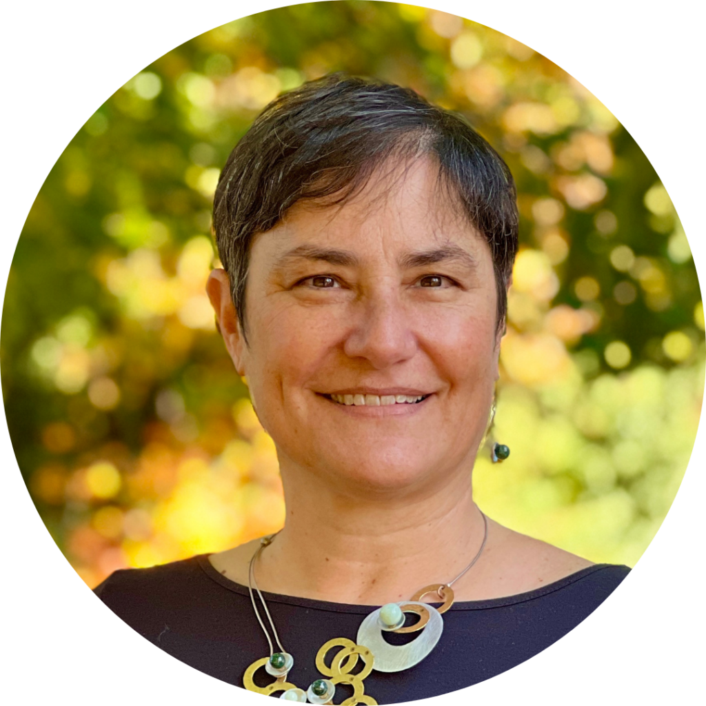 Rabbi Deborah Waxman wearing a colorful necklace in front of blurred greenery.