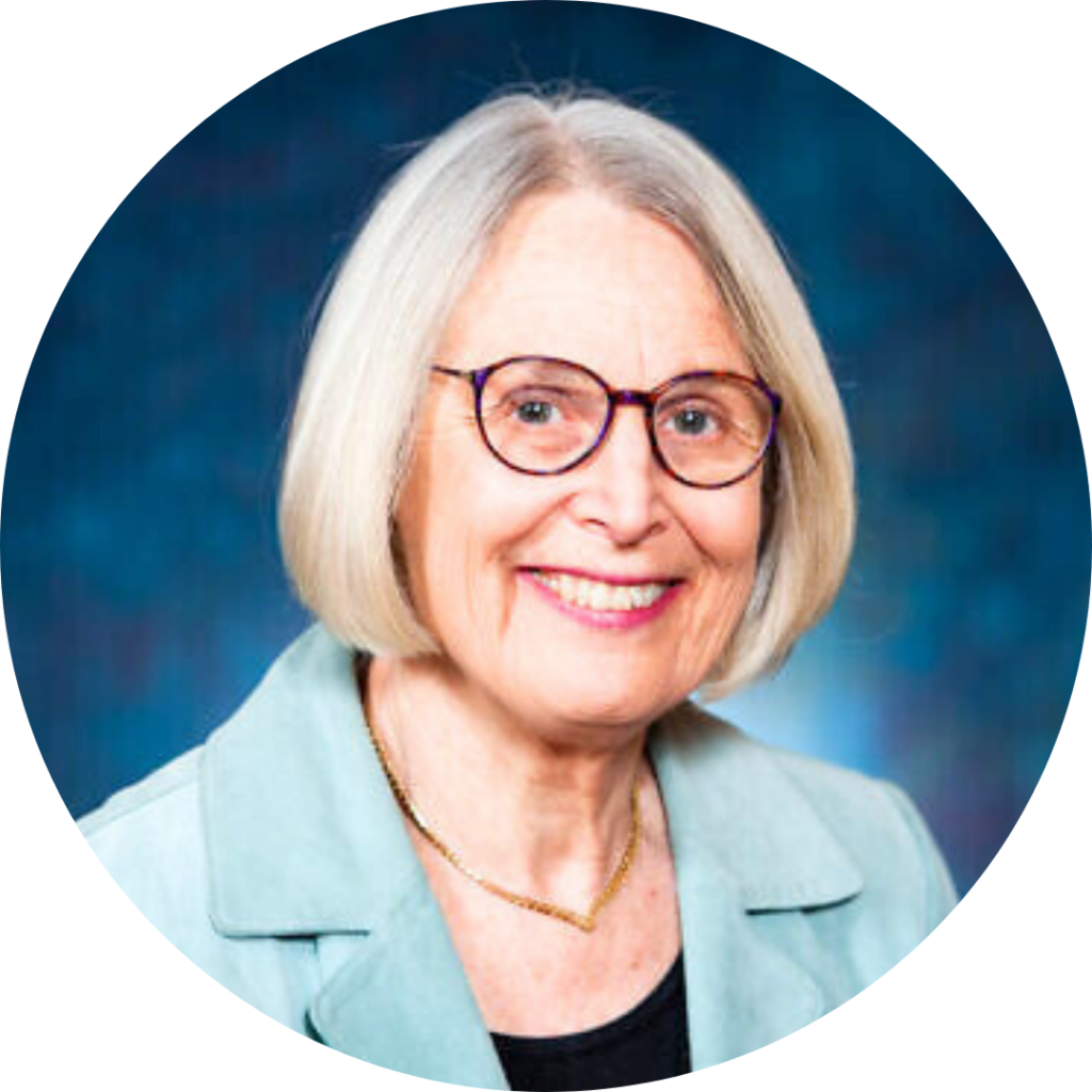 Rabbi Nancy Fuchs Kreimer wearing a turquoise blazer smiles against a blue background.