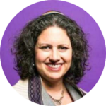 Smiling person with curly hair against a purple background.