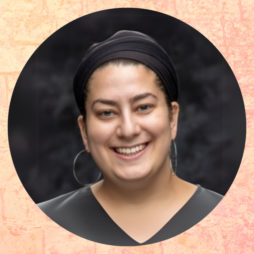 Smiling person wearing a black top and hoop earrings against a dark background.