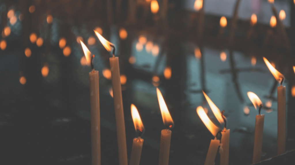Lit candles with soft, glowing flames create a warm and serene atmosphere in a dimly lit setting.