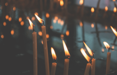 Lit candles with soft, glowing flames create a warm and serene atmosphere in a dimly lit setting.