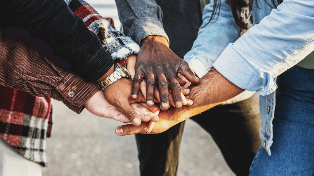 Diverse group of hands stacked together, symbolizing unity and teamwork.