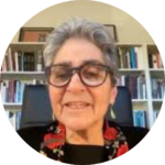 Person with short gray hair and glasses, smiling in front of a bookshelf.