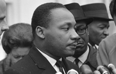 A group of people gathered, one person speaking into multiple microphones.