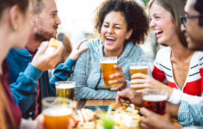 A group of friends laughing and enjoying drinks at an outdoor table.