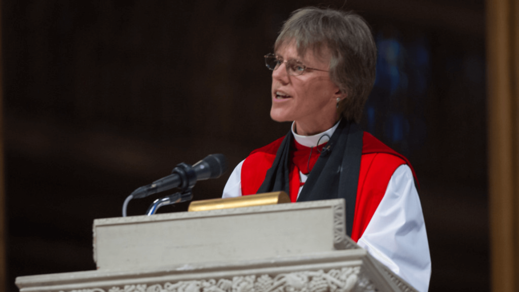 Bishop Mariann Edgar Budde wearing ceremonial garb speaking at a podium