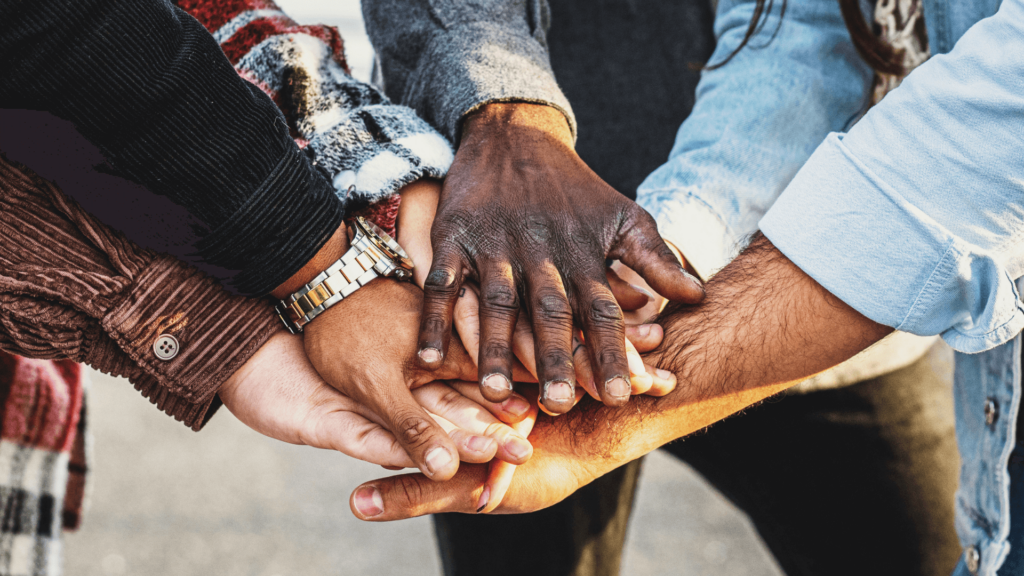 Diverse group of hands stacked together symbolizing unity and teamwork against a blurred background.