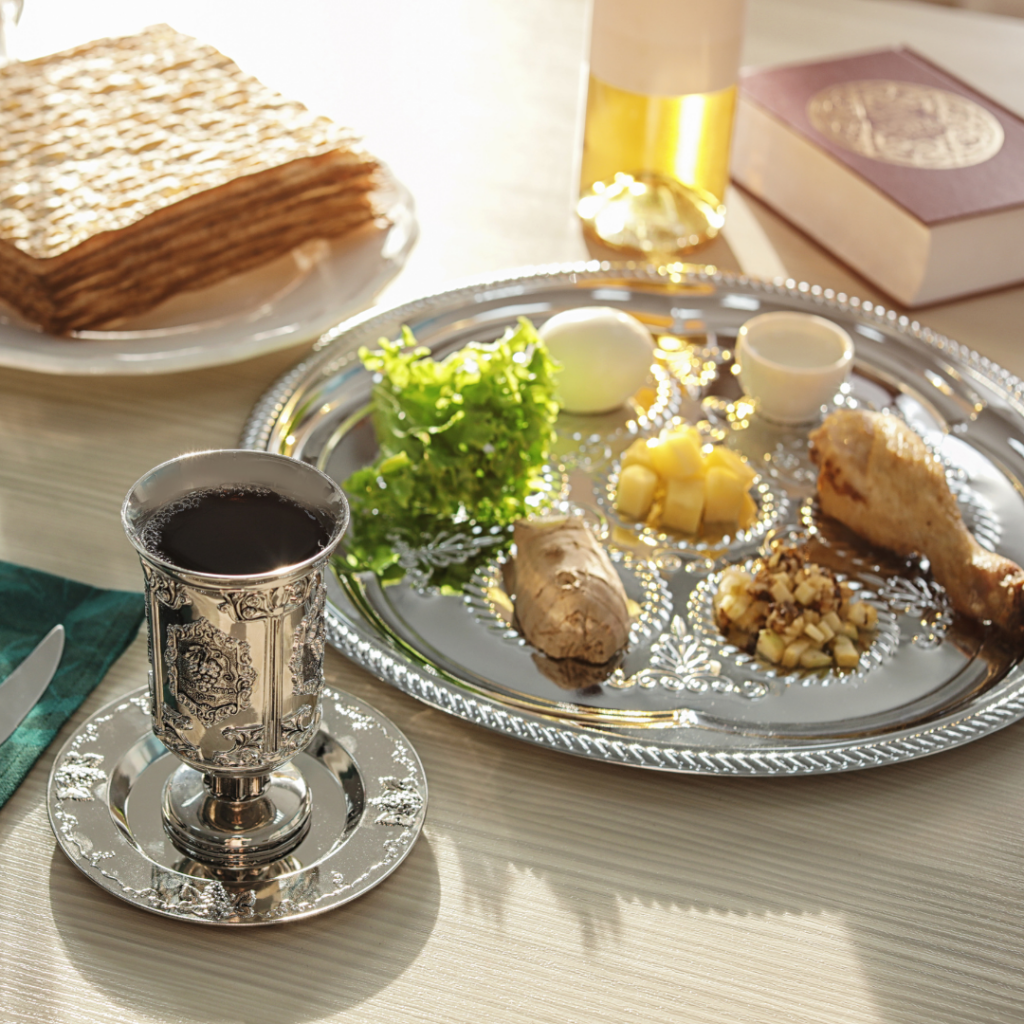 Passover Seder plate with wine, matzah, and traditional foods on a table.
