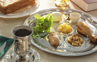 Passover Seder plate with wine, matzah, and traditional foods on a table.