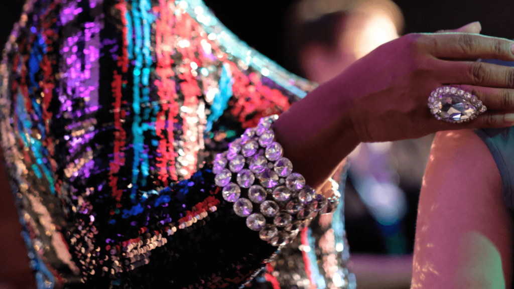 A person wearing a colorful sequined outfit and sparkly jewelry.