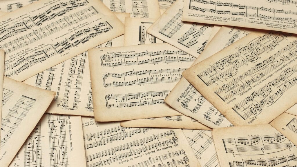 A scattered collection of vintage sheet music pages with handwritten musical notes and markings.