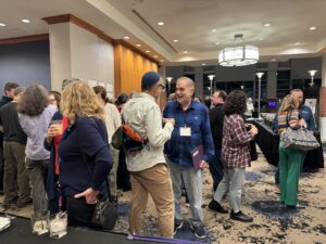 People mingle and talk at a social event in a brightly lit, modern indoor space.