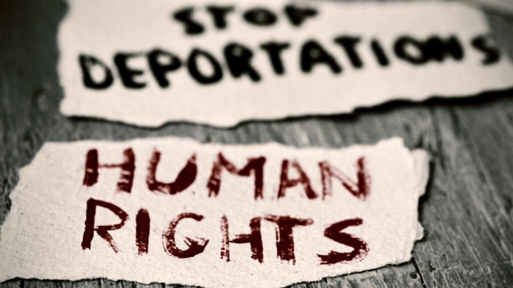 Torn paper notes read STOP DEPORTATIONS and HUMAN RIGHTS in bold, handwritten letters.