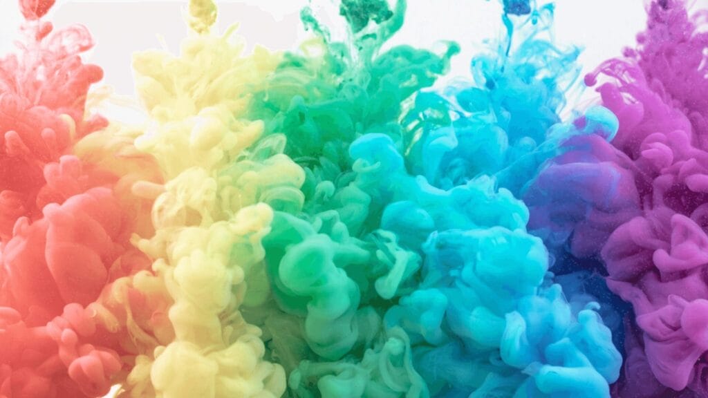 Colorful clouds of ink in water blend seamlessly from red to purple in a vibrant rainbow gradient.