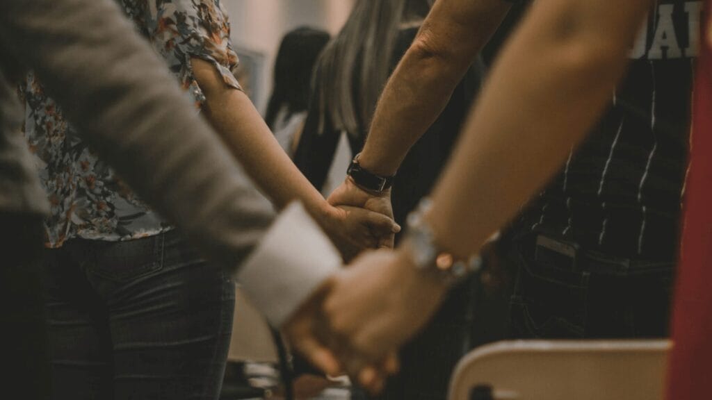 People standing close together holding hands in a group, expressing unity and support.