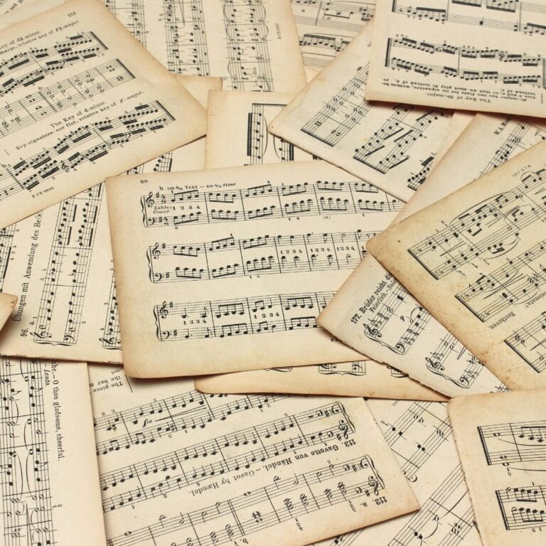 Scattered vintage sheet music pages with musical notes and lyrics on aged, yellowed paper.