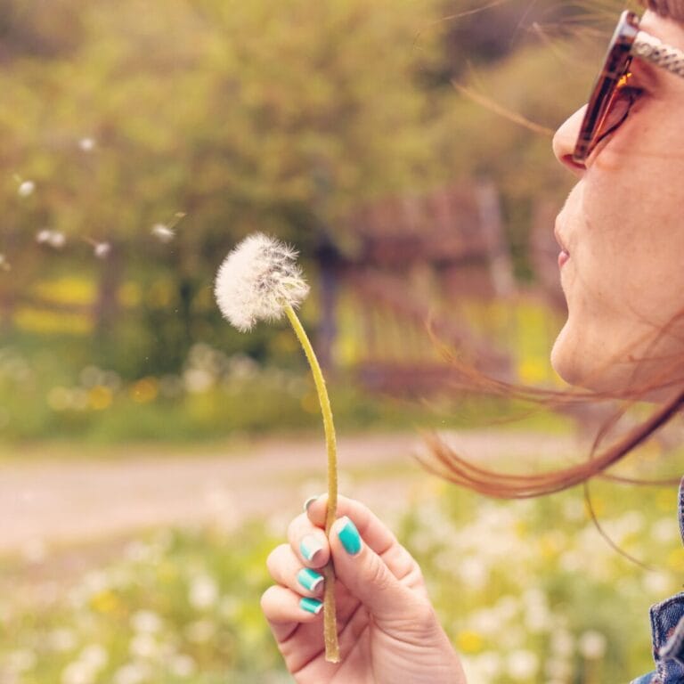 A woman blowing a dandelion.